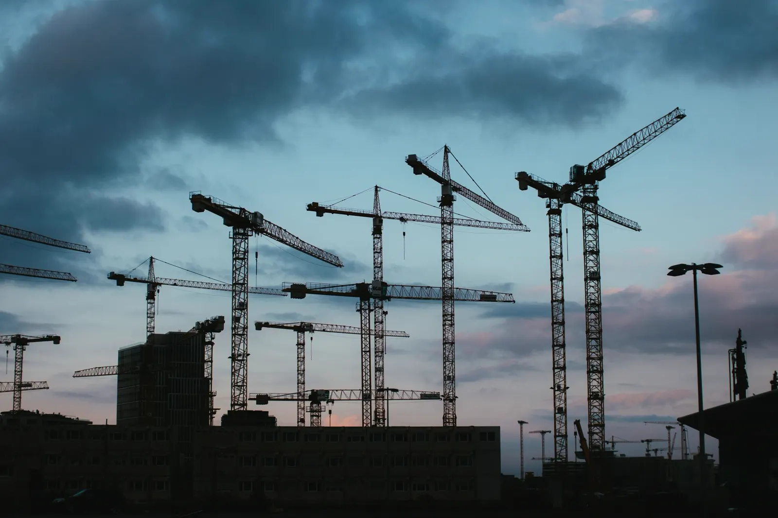 Két toronydaru egy belvárosi építkezés fölött, alkonyati fényben